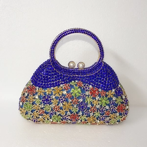 Détail d'une pochette de soirée avec strass bleus, motif floral et fermoir perle