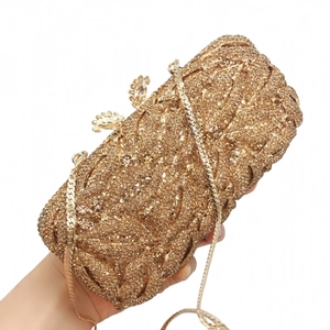 Detail of gold evening clutch bag featuring intricate leaf patterns and crystal rhinestone texture