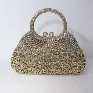 Détail de la pochette de soirée dorée avec fleurs en strass et poignée anneau cristal