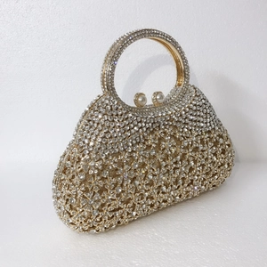 Détail d'une pochette de soirée dorée champagne avec strass floraux et fermoir perle