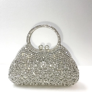 Détails d'une pochette argentée avec strass, motifs floraux et fermoir en perle