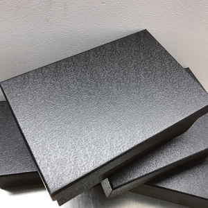 Detailed view of stackable black rectangular gift boxes with spiral embossed texture surface