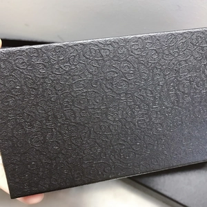 Macro shot of the intricate embossed floral texture on a black evening clutch gift box