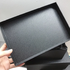Detail of elegant black gift box featuring embossed floral scroll patterns and textures