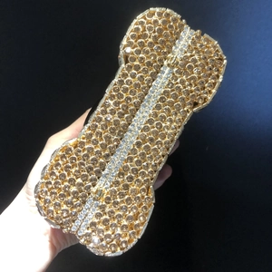 Close-up of a bone-shaped evening clutch bag with golden rhinestones and metal clasp