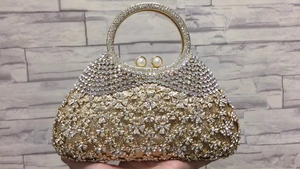 Détail d'une pochette de soirée à strass floraux avec fermoir perles et anse ronde