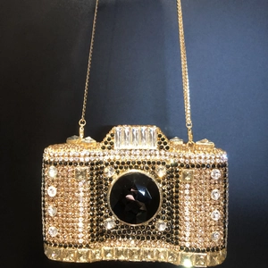 Detailed shot of camera-shaped evening bag with crystal studs and gold chain strap