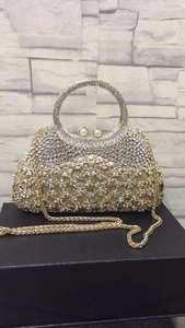 Détail du sac de soirée doré avec strass, fermoir perle et poignée en anneau métal