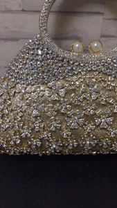 Détail d'une pochette dorée avec strass floraux et fermoir en perles élégant
