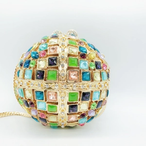 Macro view of spherical evening bag featuring colorful rhinestones and gold metal chain