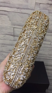 Gros plan d'une pochette de soirée dorée ornée de strass brillants et motifs floraux
