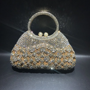 Détail de la pochette dorée à strass avec motifs floraux et fermoir en perles