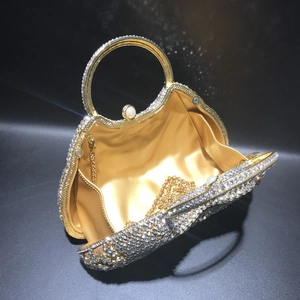 Détail de pochette de soirée dorée avec strass, fermoir perle et doublure satin