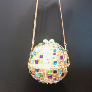 Close-up of golden hollow clutch featuring colorful crystals and a delicate chain strap