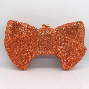 Close-up of orange rhinestone bow evening clutch bag with gold metal frame and clasp