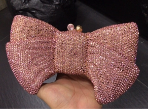 Detailed view of a pink bow-shaped clutch bag covered in sparkling rhinestones