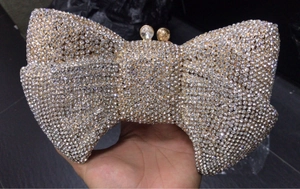 Close-up of luxury bow evening clutch bag with full rhinestone inlay and gold metal frame