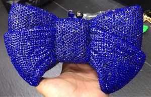 Detailed close-up of dark blue crystal bow clutch with jeweled clasp for evening events