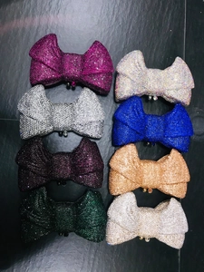 Flat lay of bow-shaped crystal evening clutch bags in eight sparkling diamond colors