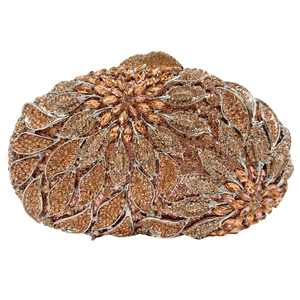 Detail of leaf patterns and sparkling crystals on a golden hollow metal evening clutch bag