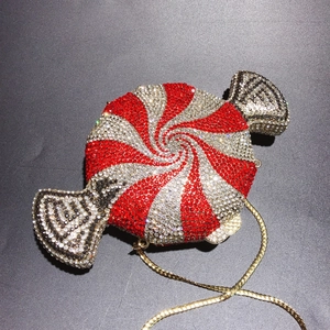 Macro shot of candy-shaped evening bag with red and silver rhinestones and gold chain