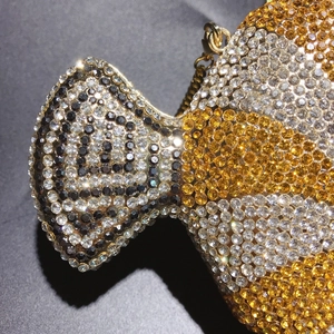 Macro detail of luxury fish-shaped clutch bag with clear and gold rhinestones and gold chain