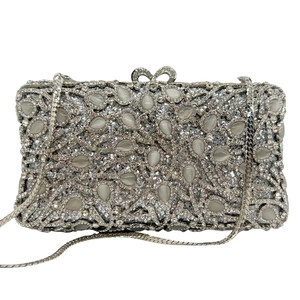 Detailed close-up of sparkling silver evening bag with teardrop cat eye stones and bow clasp