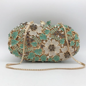 Detail of floral crystal clutch bag with green rhinestones and gold snake chain strap