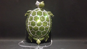 Detailed view of turtle-shaped crystal clutch bag with emerald green rhinestones and chain