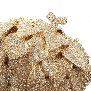 Macro shot of handcrafted gold-tone metal evening bag with dense white rhinestone leaf pattern