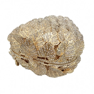 Close-up of golden grape leaf clutch bag featuring crystal embellishments and metal clasp