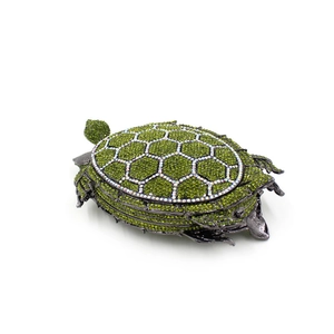 Macro detail of turtle-shaped evening bag with green rhinestones and metal frame