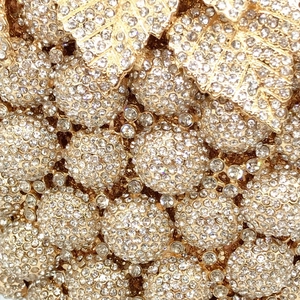 Macro detail of grape-shaped crystal clutch featuring dense rhinestones and gold leaves