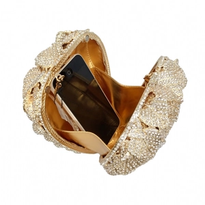 Detail of gold evening clutch bag with crystal leaves and spacious interior for phone