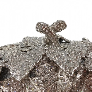 Macro detail of silver grape leaf clutch bag with sparkling rhinestone pavé setting