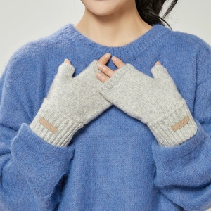 Close-up of light grey knitted fingerless gloves with soft texture and leather logo detail