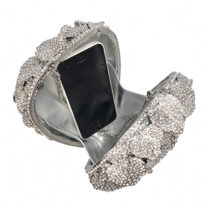 Detail view of crystal evening clutch bag with metal leaves and silver lining showing interior