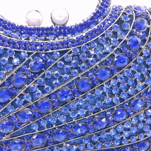 Macro shot of blue crystal rhinestones and white pearl clasp on a luxury evening clutch bag