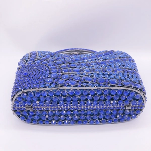 Macro view of blue rhinestones on vertical royal blue evening clutch with metal frame