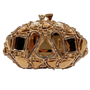Close-up of gold hollow metal frame with champagne crystals on luxury evening clutch