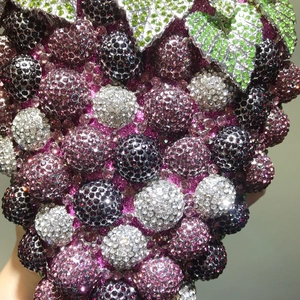 Close-up of a grape-shaped evening clutch bag with purple and green sparkling crystals