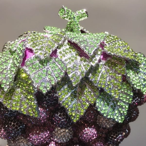 Macro detail of the grape shaped evening bag featuring dense hand-set green and purple crystals