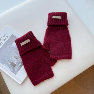 Detail of dark red chunky knit fingerless gloves with a vintage leather brand label