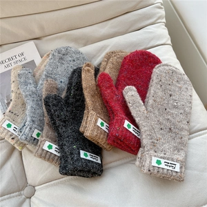 Winter thick knit mittens in multiple colors with clover patches on white sofa