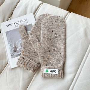 Detailed knit texture of warm oatmeal mittens with ribbed cuffs and fashion clover patch