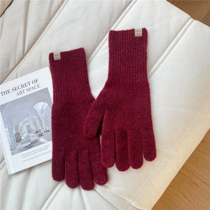 Close-up of wine red knitted gloves with thick ribbed cuffs and a sewn brand label