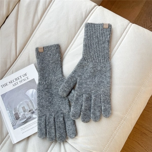 Close-up of gray knit gloves with long cuffs and a brown leather SOWLOW logo patch