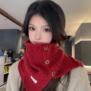 Detail of red cable-knit neck warmer with round wooden buttons and branded woven label