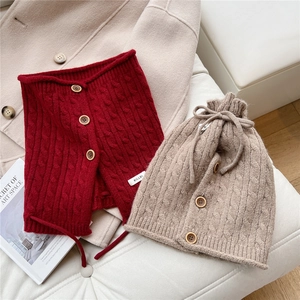 Detail of red cable knit neck warmer and oatmeal beanie with decorative wooden buttons