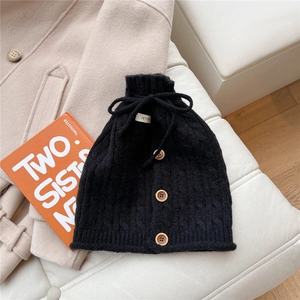 Close-up of black knit neck warmer with wooden buttons and drawstring detail